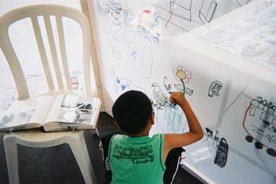 Back view of a young boy making a wonderful drawing of a pigeon near ground level in the drawing tent
